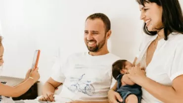 Eine Familie lächelt und verbringt Zeit miteinander auf dem Bett.