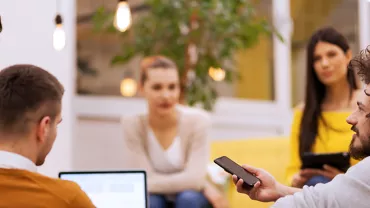 Gruppe von Menschen in einem Gespräch mit Laptops und Smartphones.