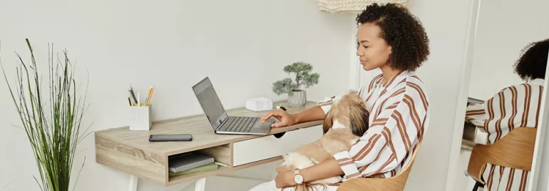 Frau nutzt flexible Arbeitsmöglichkeiten, indem sie remote von ihrem organisierten Home-Office aus mit einem Laptop arbeitet.